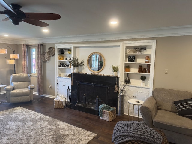 living area with crown molding, baseboards, ceiling fan, a fireplace, and wood finished floors