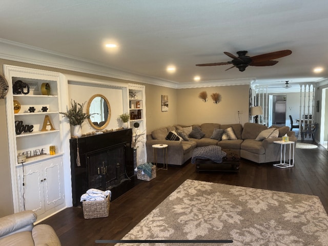 living room with ornamental molding, built in features, dark wood-style floors, recessed lighting, and a fireplace