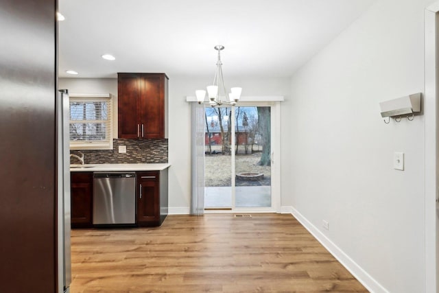 kitchen with baseboards, an inviting chandelier, light countertops, appliances with stainless steel finishes, and backsplash