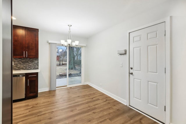 unfurnished dining area featuring baseboards, light wood-type flooring, and a chandelier