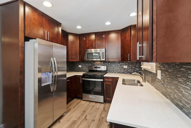 kitchen with tasteful backsplash, light wood-type flooring, recessed lighting, stainless steel appliances, and a sink