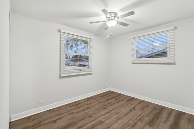 unfurnished room with visible vents, a ceiling fan, baseboards, and dark wood-style flooring