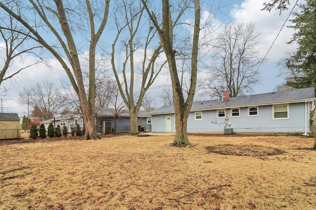 rear view of property featuring central AC unit, fence, and a chimney