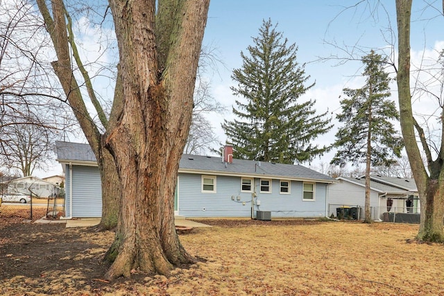 back of property with cooling unit, a chimney, and fence