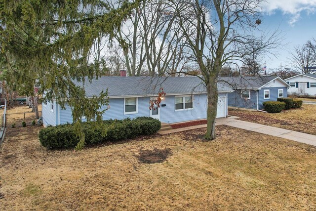 ranch-style house with concrete driveway, a chimney, a garage, and a front lawn