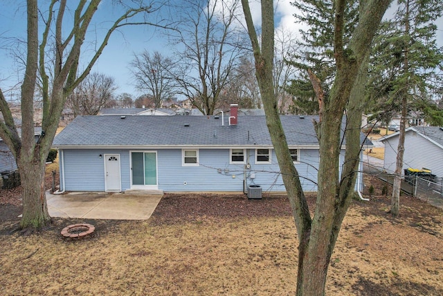 back of house featuring fence, an outdoor fire pit, central AC unit, a chimney, and a patio area