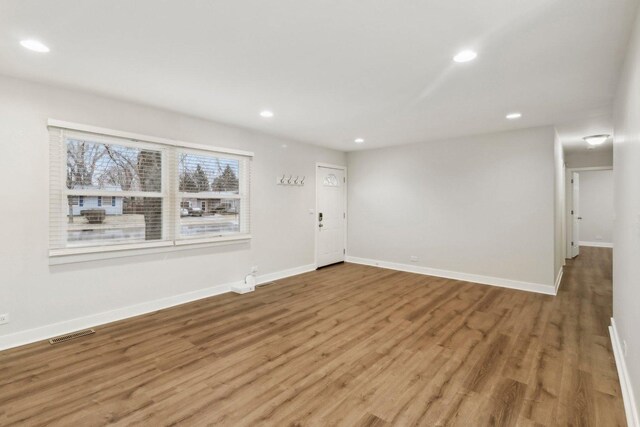 unfurnished living room featuring recessed lighting, baseboards, light wood-style floors, and an inviting chandelier