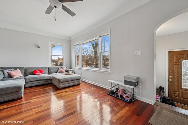 living room with baseboards, arched walkways, ceiling fan, and hardwood / wood-style flooring