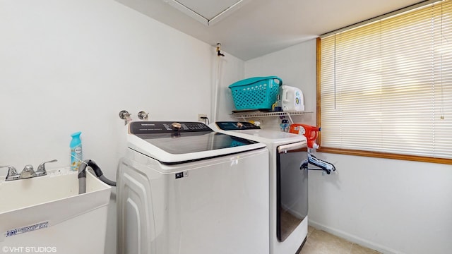 clothes washing area with washer and dryer, laundry area, baseboards, and a sink