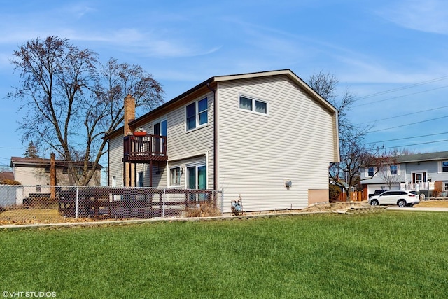 back of property with a balcony, a chimney, a yard, and fence