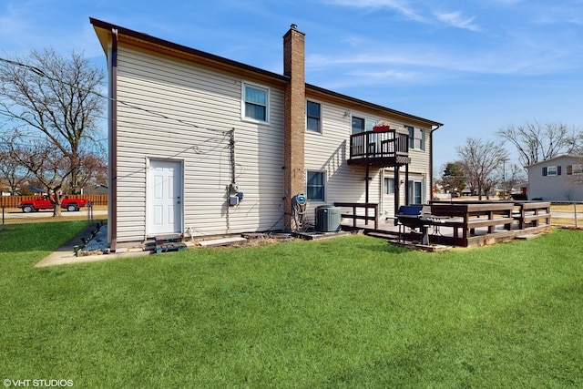 rear view of house with a balcony, central air condition unit, a yard, and a chimney