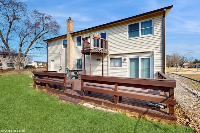 back of property with a balcony, a yard, fence, and a chimney