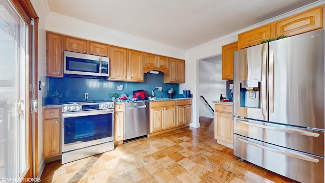 kitchen with appliances with stainless steel finishes, crown molding, and a sink