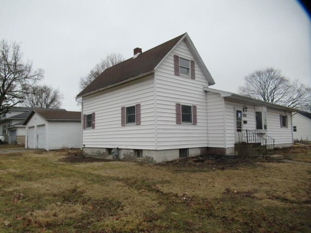 rear view of property with an outbuilding, a lawn, a chimney, and a garage