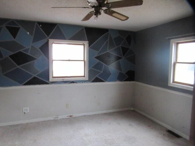 spare room featuring visible vents, baseboards, ceiling fan, and carpet flooring