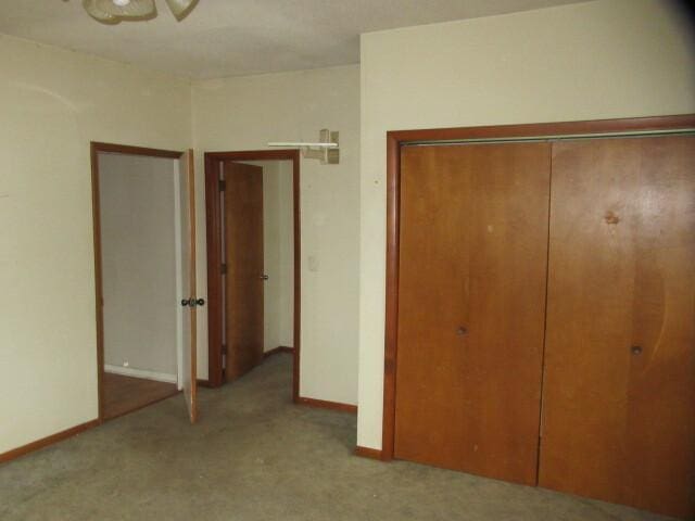 unfurnished bedroom featuring a closet, baseboards, and carpet