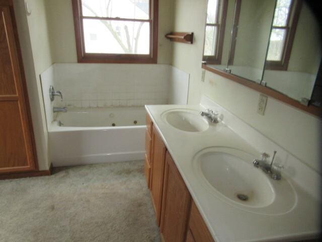 bathroom with a sink, a jetted tub, and double vanity