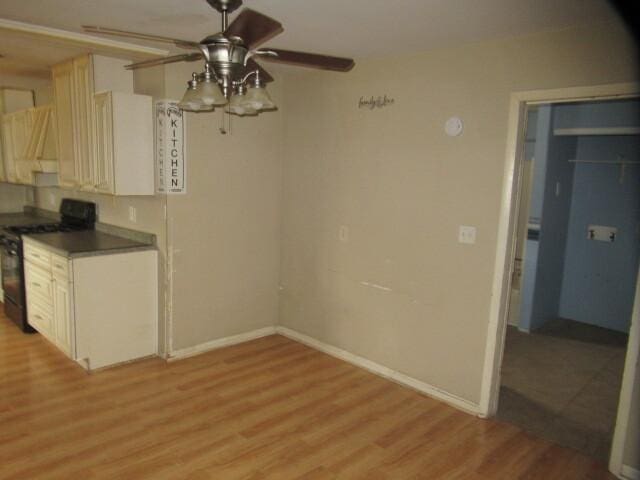 unfurnished dining area featuring a ceiling fan, baseboards, and light wood finished floors