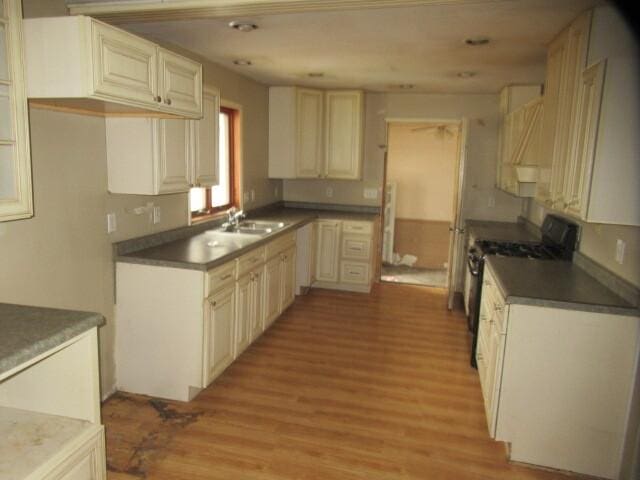 kitchen featuring range with gas stovetop, light wood-type flooring, and a sink