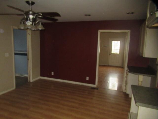 unfurnished dining area featuring light wood-style flooring, a ceiling fan, and baseboards