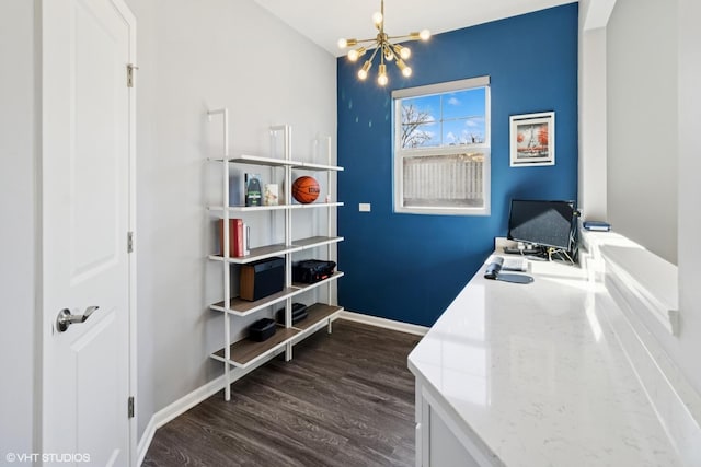 laundry area featuring dark wood-type flooring, a notable chandelier, and baseboards