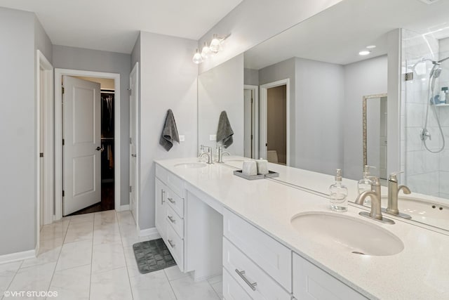 bathroom with double vanity, tiled shower, and a sink