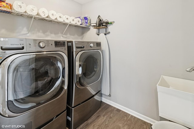 washroom featuring washing machine and clothes dryer, laundry area, dark wood-type flooring, and baseboards