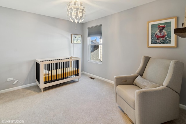 carpeted bedroom featuring visible vents, baseboards, a notable chandelier, and a crib