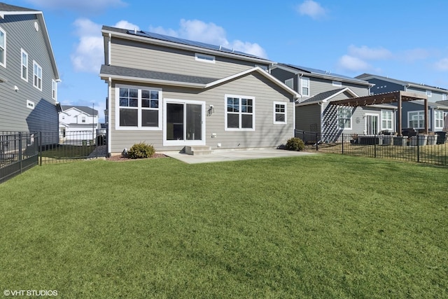 back of property with a yard, a patio, solar panels, and a fenced backyard