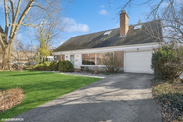 new england style home featuring brick siding, aphalt driveway, a front yard, a chimney, and an attached garage