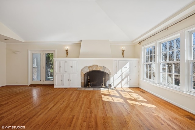 unfurnished living room with visible vents, high vaulted ceiling, a high end fireplace, light wood-style floors, and baseboards