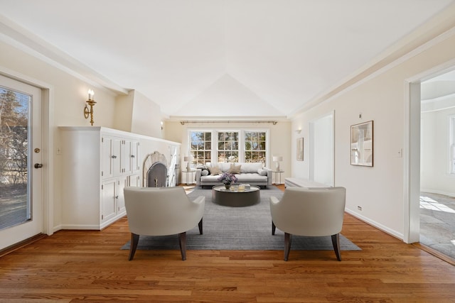 living room featuring light wood-type flooring, baseboards, and vaulted ceiling