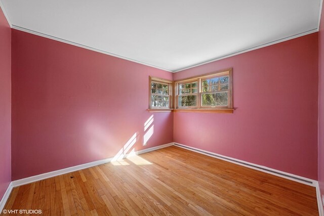 empty room with light wood-style flooring, baseboards, and ornamental molding