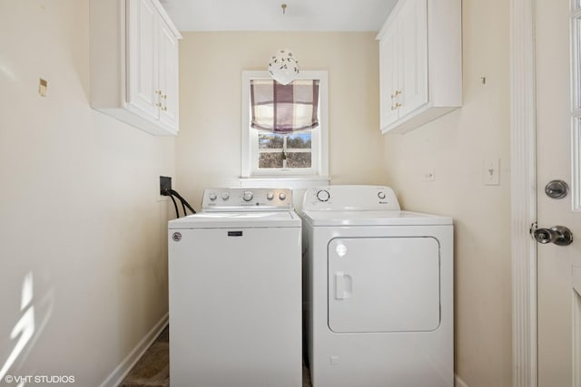 laundry area featuring baseboards, cabinet space, and washer and clothes dryer