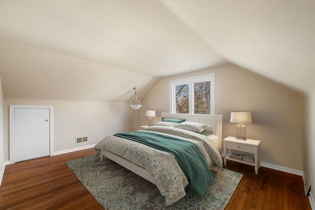 bedroom with vaulted ceiling, wood finished floors, visible vents, and baseboards