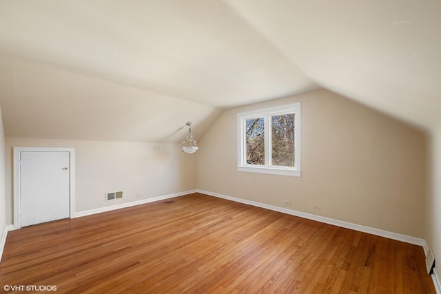 additional living space featuring lofted ceiling, baseboards, visible vents, and light wood finished floors