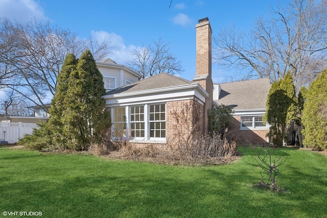 exterior space with a yard, brick siding, a chimney, and fence