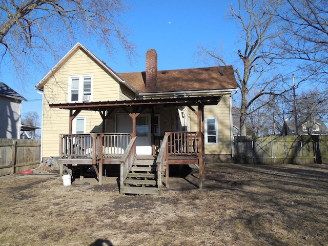 back of property with a gate, a chimney, a deck, and fence