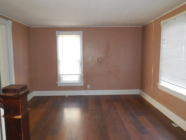 unfurnished room featuring baseboards, wood finished floors, and crown molding