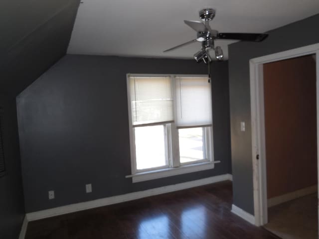 interior space with baseboards, dark wood finished floors, a ceiling fan, and vaulted ceiling