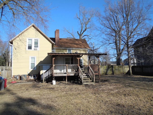 back of house with a deck, a chimney, and fence