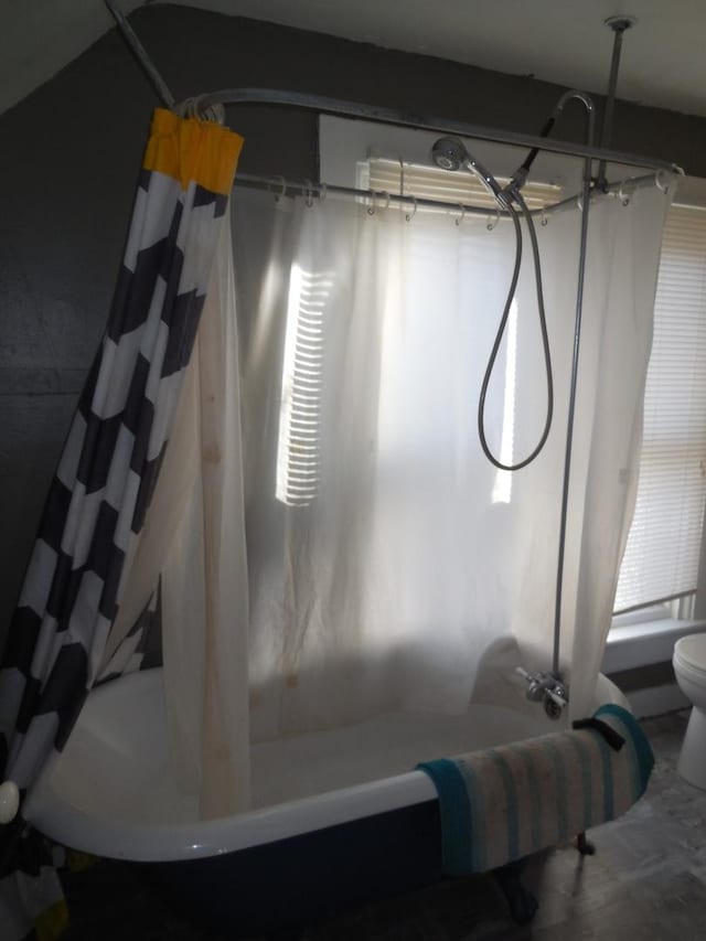 interior space featuring shower / bath combination with curtain and toilet