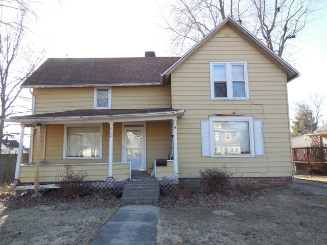 view of front of home featuring a shingled roof, covered porch, and a chimney