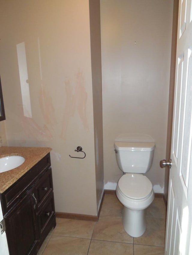 half bathroom with baseboards, toilet, vanity, and tile patterned flooring