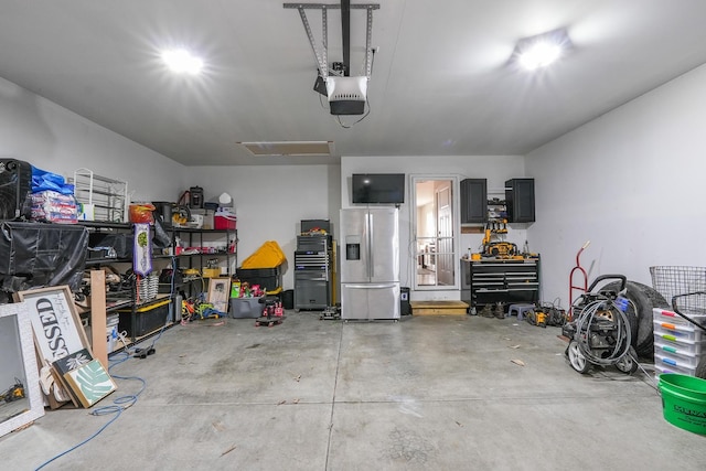 garage with a garage door opener and stainless steel refrigerator with ice dispenser