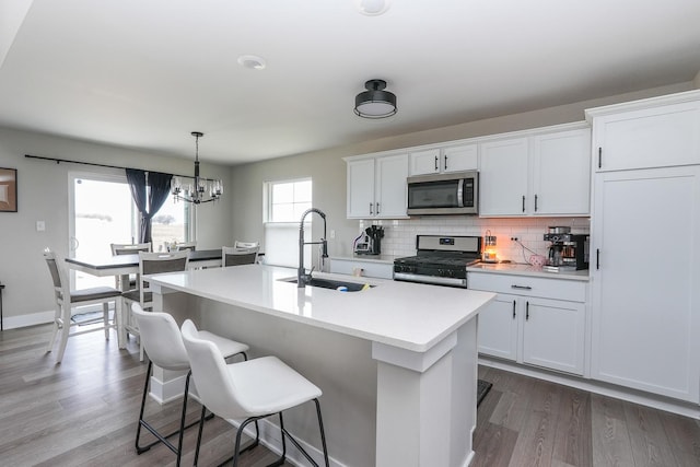 kitchen with a center island with sink, a kitchen bar, light countertops, stainless steel appliances, and a sink