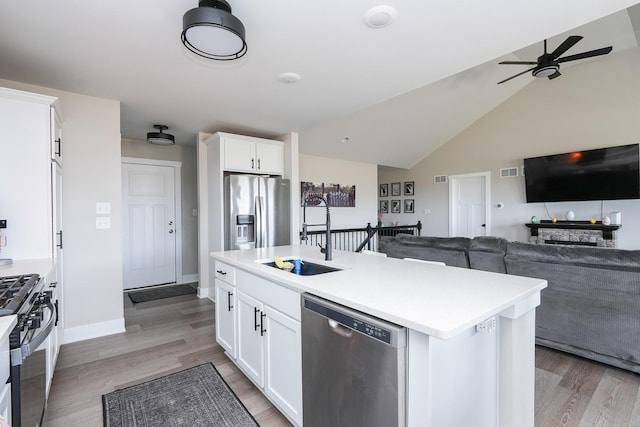 kitchen featuring ceiling fan, a sink, appliances with stainless steel finishes, white cabinetry, and open floor plan