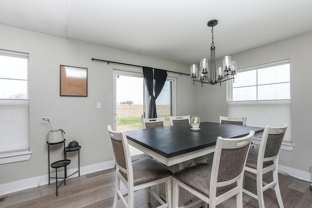 dining area with a notable chandelier, visible vents, baseboards, and wood finished floors