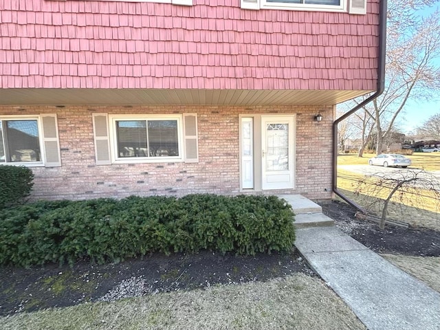 doorway to property with brick siding and mansard roof