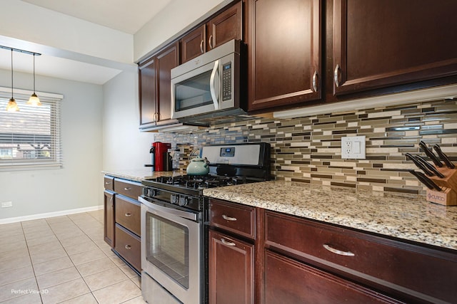 kitchen featuring light tile patterned floors, light stone counters, hanging light fixtures, appliances with stainless steel finishes, and backsplash